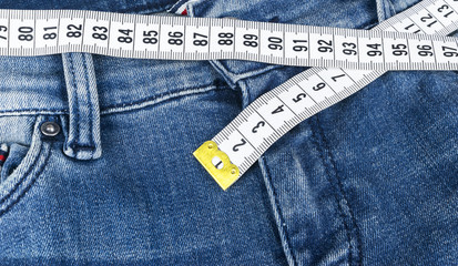 A blue woman jeans and ruler, concept of diet and weight loss. Jeans with measuring tape. Healthy lifestyle, dieting, fitness. Weight control. Successful diet. Reducing excess weight