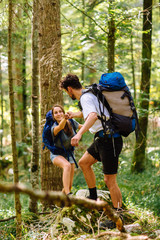 Hiking couple. Young couple with backpacks walking through the forest 