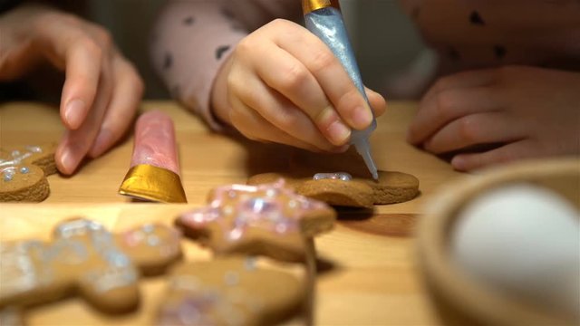 Young mother and her cute little daughter prepare Christmas cookies. Close up of hends