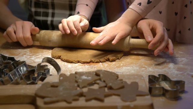 Young mother and her cute little daughter prepare Christmas cookies. Close up of hends