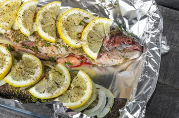 raw trout, fish with spices, herbs and lemon in a baking dish top view