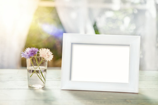 Empty frame mockup with flowers in glass