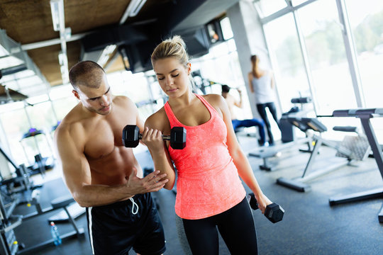 Young adult woman doing exercises in gym with trainer