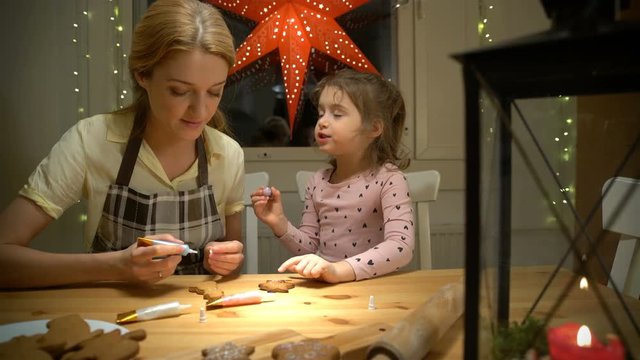 Young mother and her cute little daughter prepare Christmas cookies