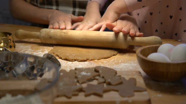 Young mother and her cute little daughter prepare Christmas cookies. Close up of hends