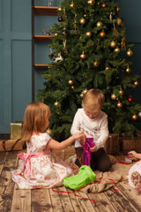 Adorable children sitting next to Christmas tree