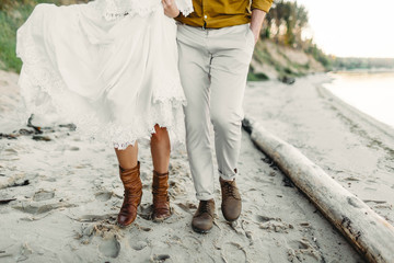A young couple is walking on the sea coastline. Close-up image of legs. Artwork