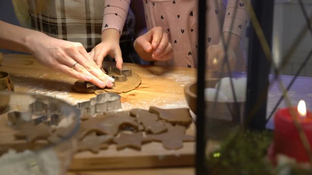 Young mother and her cute little daughter prepare Christmas cookies. Close up of hends