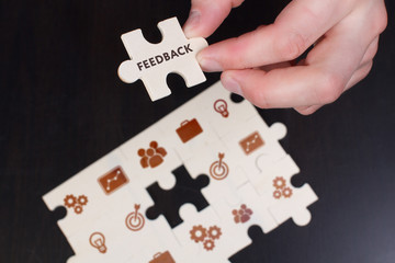 The concept of business, technology, the Internet and the network. A young businessman collects a puzzle with the proper inscription: Feedback