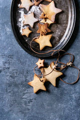 Homemade shortbread star shape sugar cookies different size with sugar powder on thread in vintage metal tray over blue texture surface. Christmas treat background. Top view with space
