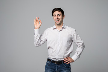 Happy okay man. Young handsome man in casual shirt gesturing okay and smiling at camera against grey background. Body language and signs. Success concept