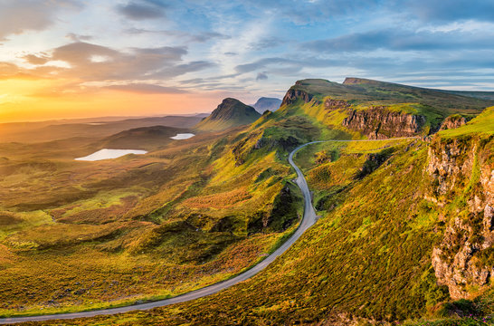 Fototapeta Long winding road at Quiraing on the Isle of Skye with a beautiful vibrant sunrise sky.