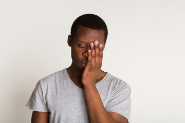 Tired young black man portrait. Hand covering face