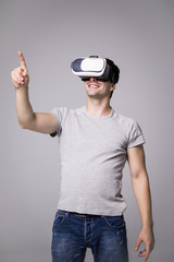 Man wearing virtual reality goggles. Studio shot, gray background