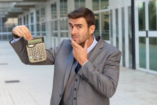 Fearful businessman showing a calculator with space for copy