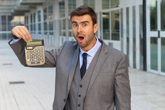 Shocked businessman showing a calculator with space for copy