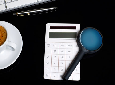 Magnifying glass and calculator on desk