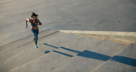 Panoramic crop of female jogger running on stairs