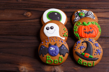 Halloween ginger biscuits set with funny decorations made of confectionery mastic on wooden kitchen table, copy space. Halloween sweets, homemade confectionery, holiday food, trick or treat concept