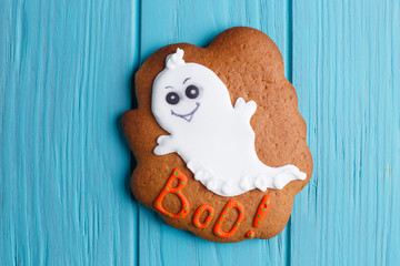 Fresh halloween gingerbread cookie with ghost decoration on white wooden table, close up