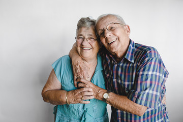 Happy senior couple looking at camera on white background