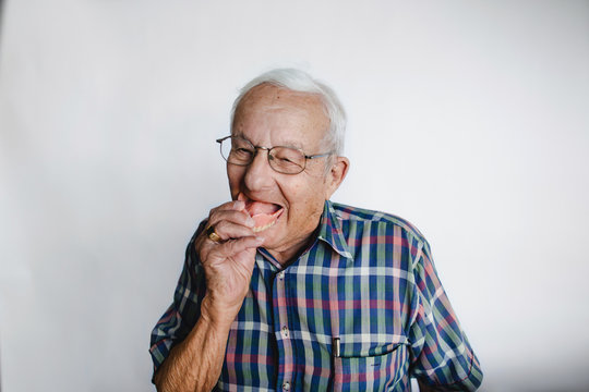 Playful senior man removing dentures and laughing