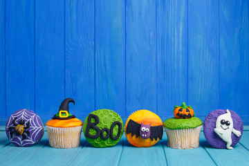 Delicious Halloween cupcakes set with bright decorations made of confectionery mastic. Halloween sweets, homemade confectionery, holiday food, trick or treat concept