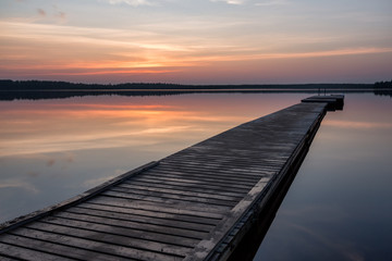 Fototapeta na wymiar Beautiful sunrise on the like with pier on foreground