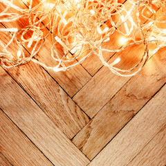 Christmas glowing  lights garland on a old antique wooden parquet floor, sparkling  garland. Christmas background with festive decoration.