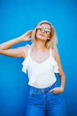 Blonde with white shirt and sunglasses on a blue background