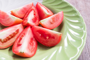 Fresh tomato slice in plate on wood background