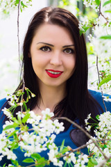 Naklejka premium Young beautiful woman in spring blossoming garden