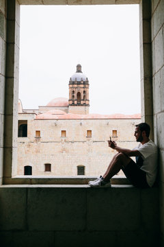Young man sitting on a stone wall inside a lookout window with views
