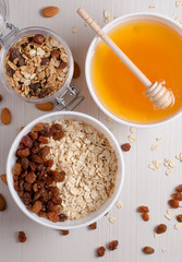 Healthy Breakfast. Oatmeal with raisins in white bowl. Almonds, honey on white  table background