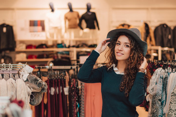 Young adult woman trying on hat in a retail store.