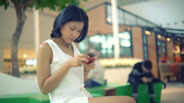 Thai Lady sits in shopping center and typing on smartphone 4k UHD (3840x2160)

