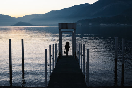 Silhouette of a woman on the jetty at lake