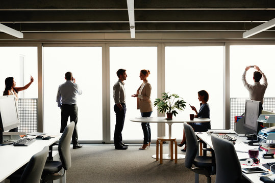 Profile silhouette of business team close to windows mulittasking