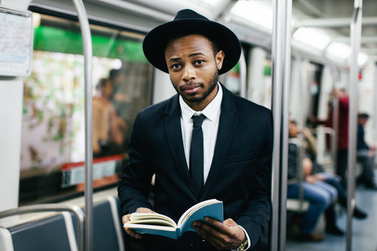 Stylish businessman reading a book on subway.