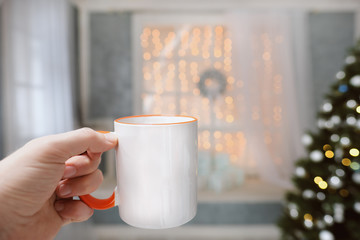 A cup with a hot drink in the hand on a background of Christmas decorations