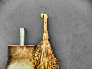 Small broom and dustpan on a grey wall background