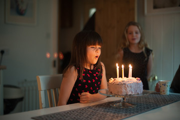 Little girl blowing out candles on her birthday cake