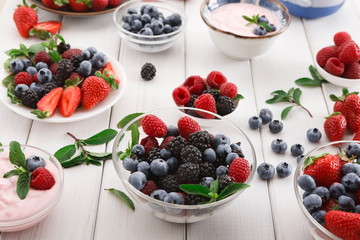 Healthy breakfast with berries and yogurt on white wooden table
