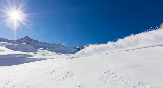 Young man snowboarder running downhill in powder snow, Alpine mountains.