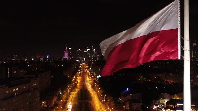 Flaga Polski na tle centrum Warszawy nocą