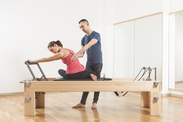 Pilates lesson on reformer, personal coaching young beautiful woman