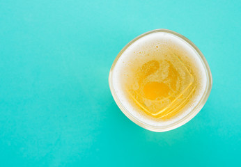 Top view of a glass of beer on green mint background
