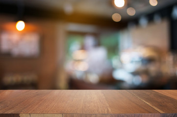 empty wooden desk over blurred coffee shop background