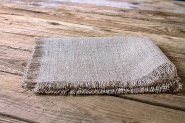 Folded linen napkin on old wooden kitchen table.