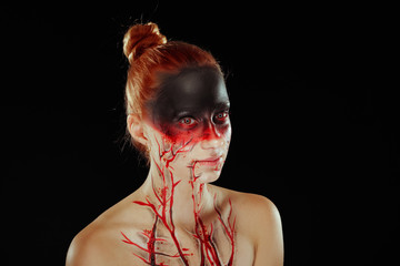 Mystic hero, bloody girl with blood on her face on a dark background. Fantasy horrible and Halloween makeup.